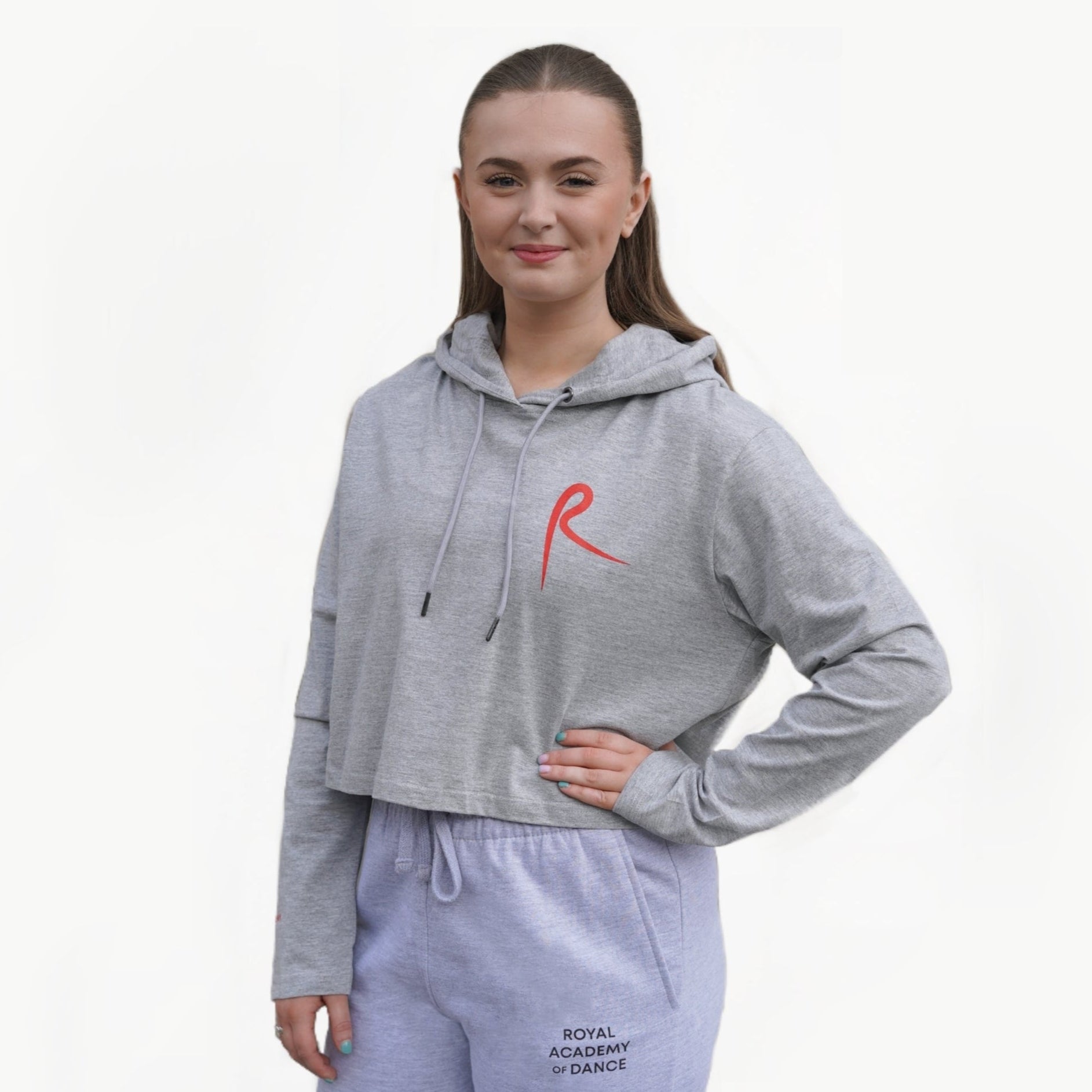 Heather grey cropped hoodie with a red arabesque symbol on the front and the Royal Academy of Dance logo on the cuff.