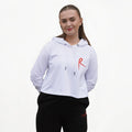 White cropped hoodie with a red arabesque symbol on the front and the Royal Academy of Dance logo on the cuff, paired with black pants.