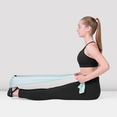 Woman using a resistance band for leg exercise on a white background