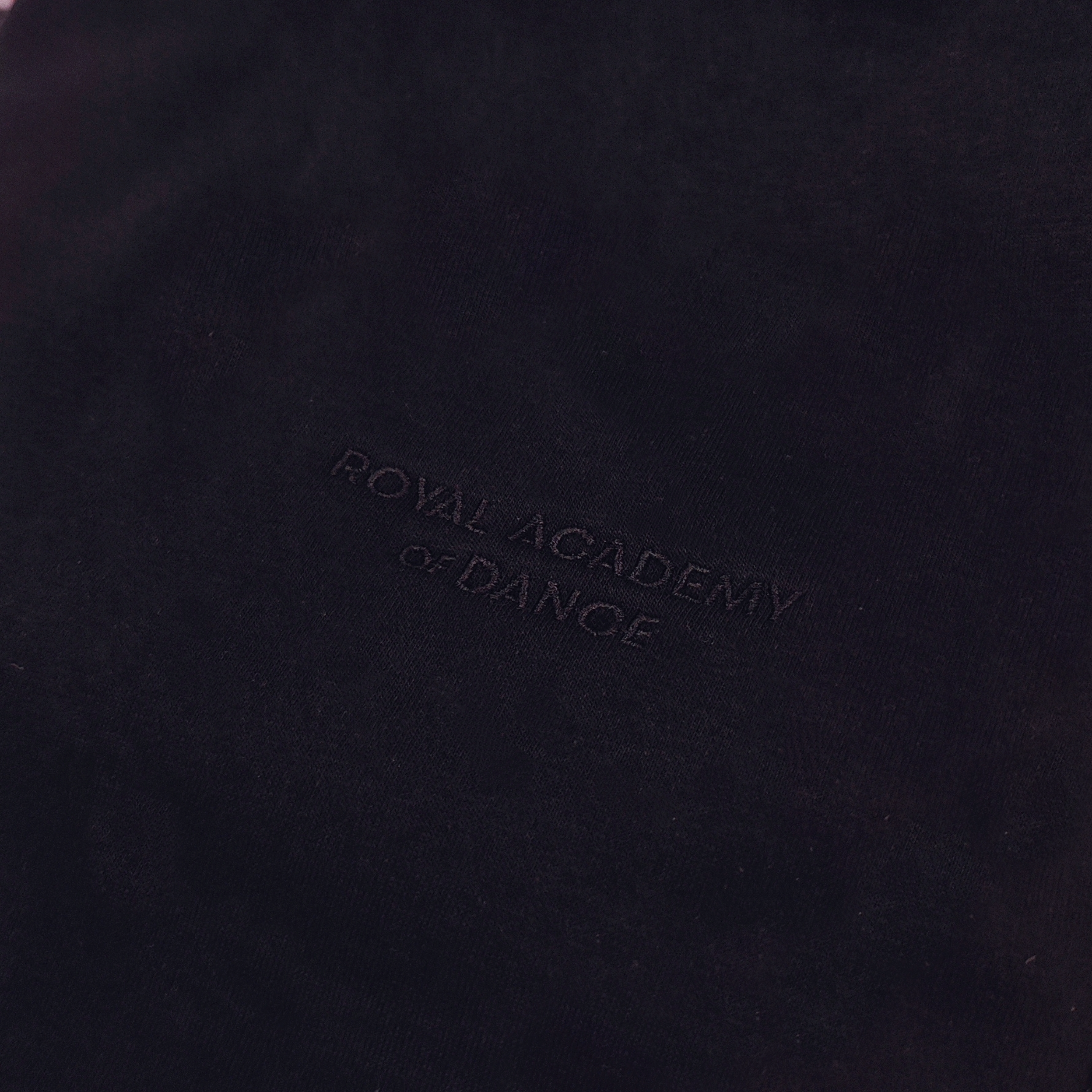 Black jogger with embroidered " Royal Academy of Dance" logo close up 