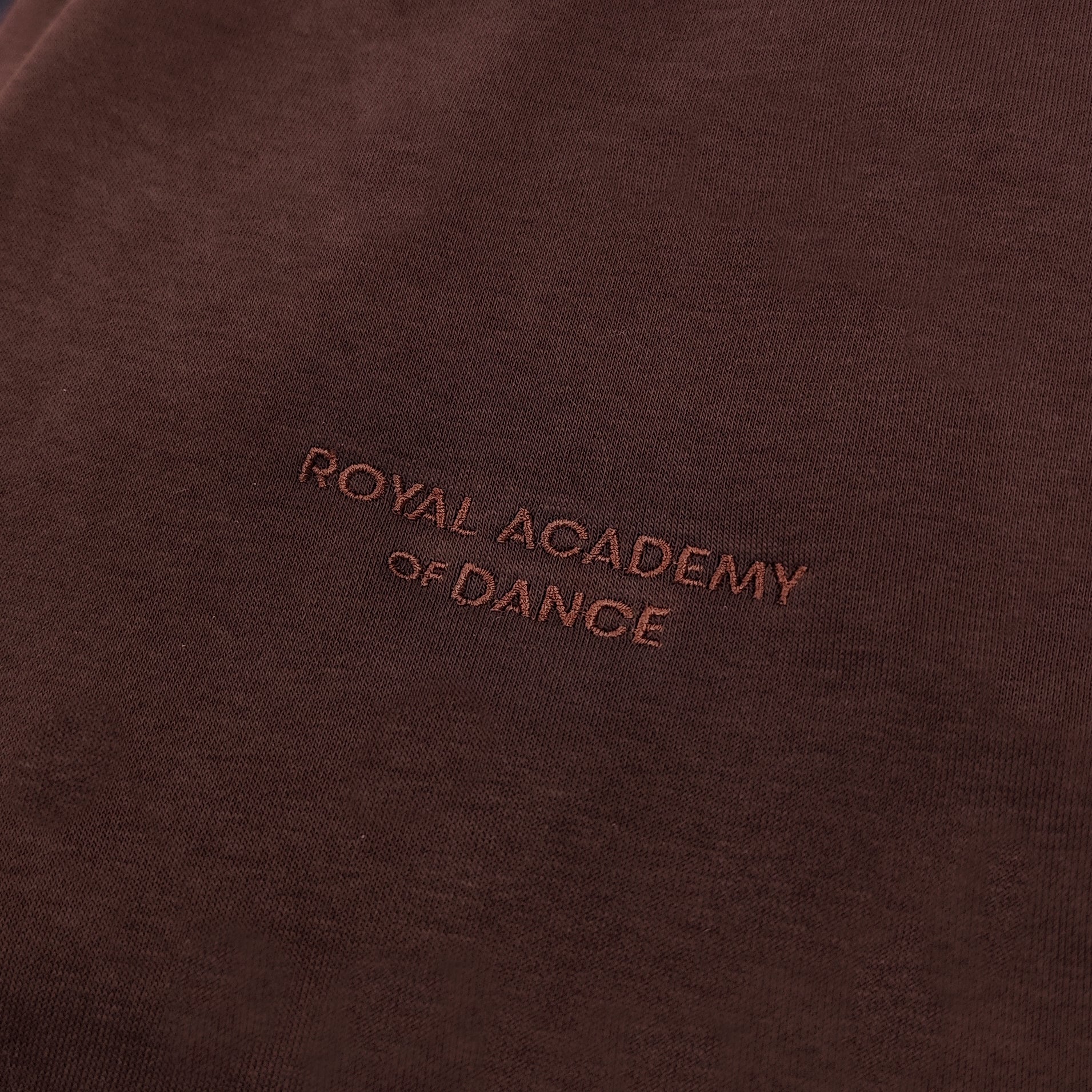 Brown jogger with embroidered " Royal Academy of Dance" logo close up 