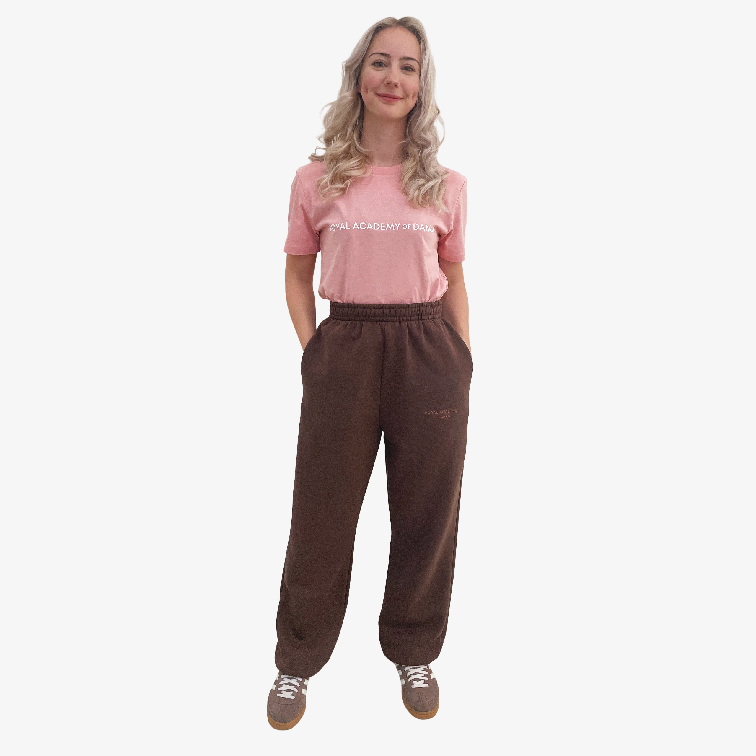 Woman wearing a pink t-shirt with 'Royal Academy of Dance' logo in white and brown jogger