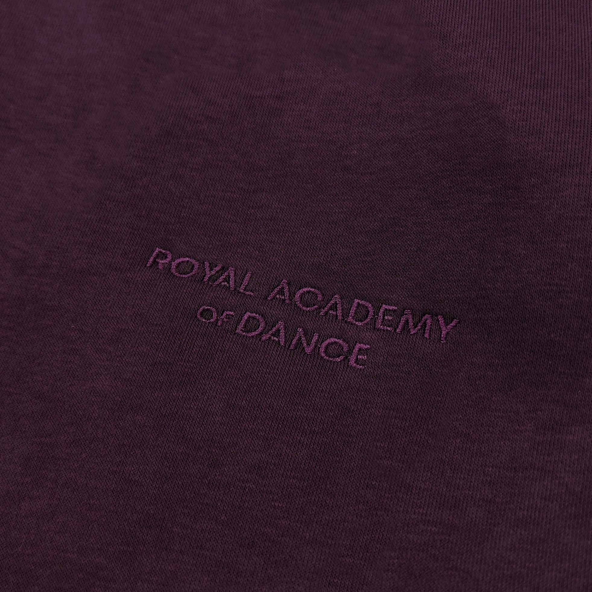 Purple jogger with embroidered " Royal Academy of Dance" logo close up