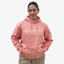  Person wearing a pink hoodie with 'Royal Academy of Dance' text 