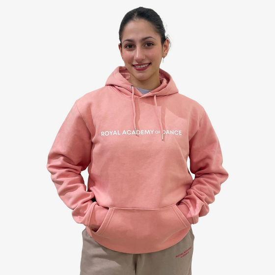 Person wearing a pink hoodie with 'Royal Academy of Dance' text 