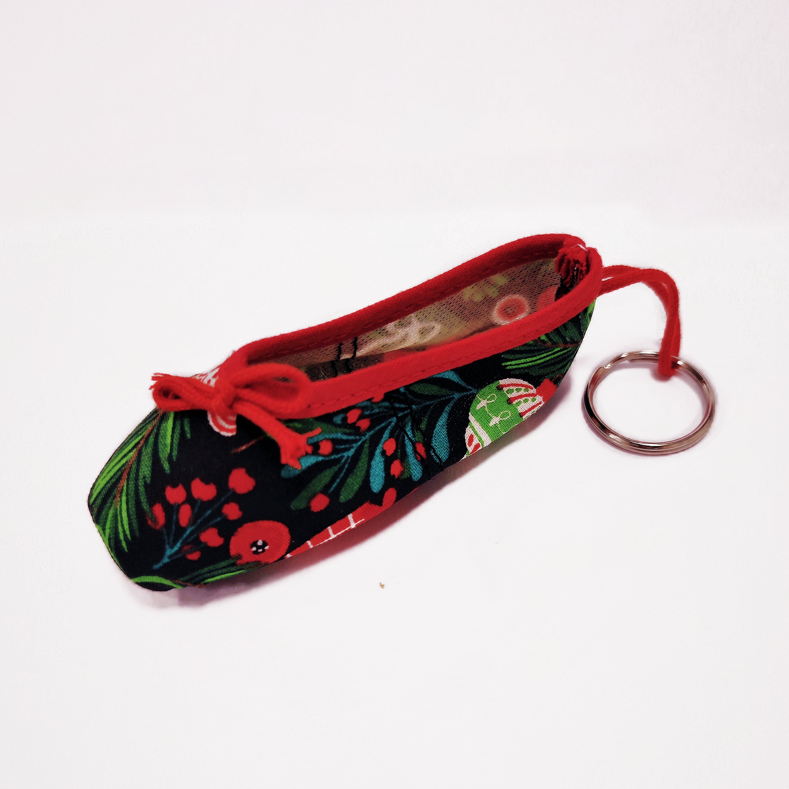 Keychain shaped like a ballet shoe with floral pattern and red bow on a white background