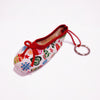 A miniature pointe shoe keyring with a canvas finish and red shoelaces, featuring a Christmas-themed design with snowflakes and stars.