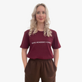 Woman wearing a burgundy  t-shirt with 'Royal Academy of Dance' logo in white