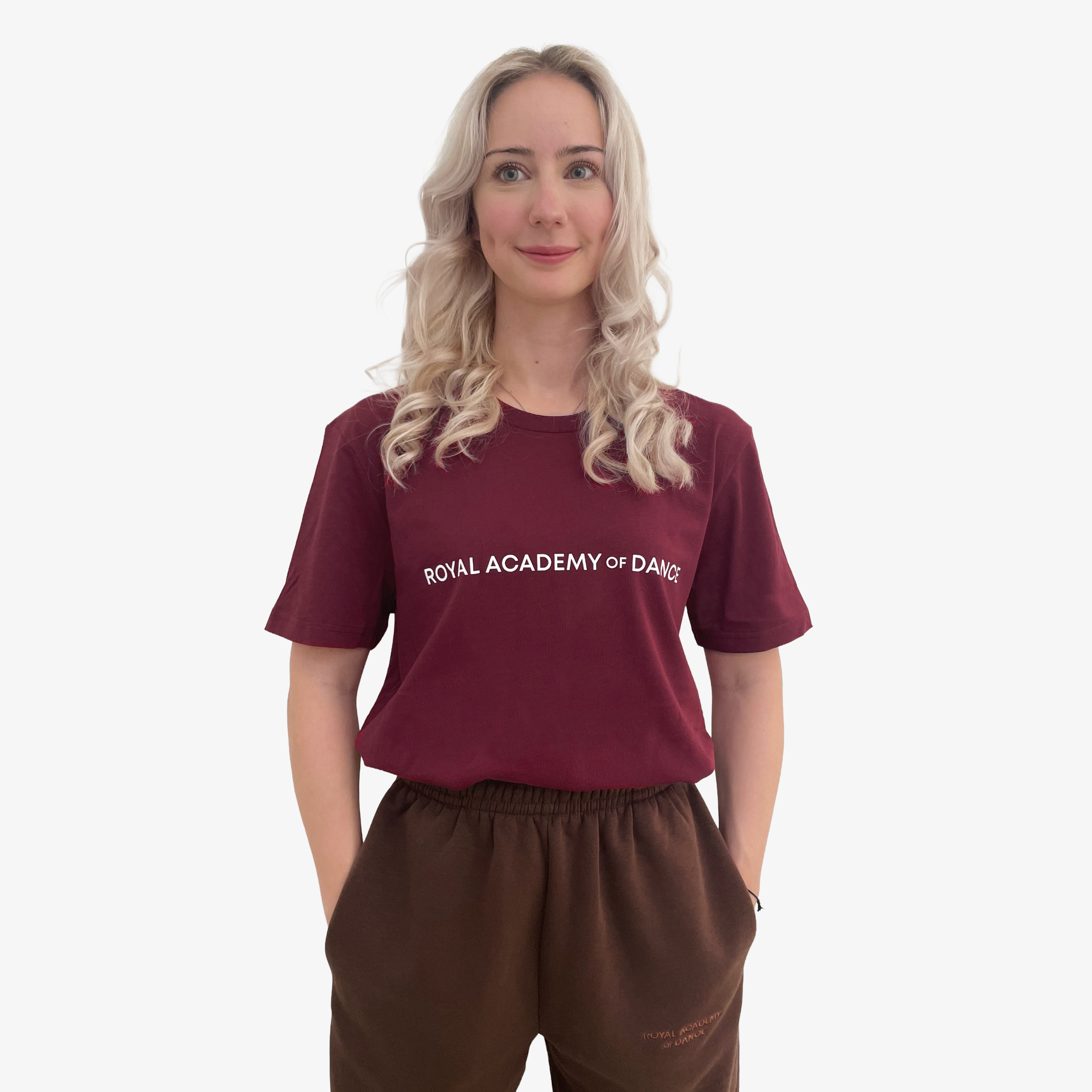 Woman wearing a burgundy  t-shirt with 'Royal Academy of Dance' logo in white