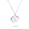 A close-up of a delicate spinning disc pendant on a necklace. The circular disc is shown mid-spin, creating a slight blur that hints at its movement. One side features a finely engraved ballerina poised in a graceful arabesque, while the opposite side reveals the formal crest of the Royal Academy of Dance. The disc hangs from a sleek chain, capturing a moment of dynamic elegance where dance and heritage revolve together.