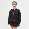 Black cropped hoodie with a front zip and kangaroo pockets, as well as ribbed cuffs with thumbhole detailing. The hoodie features the text 'RAD' on the front and Royal Academy of Dance on cuff in red. 