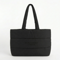 This oversized black quilted puffer tote bag features the Royal Academy of Dance logo, blending a professional ballet aesthetic with new streetwear trends. Designed as a spacious dance bag for dancers on the go, the lightweight padded nylon and soft cloud-like texture provide a stylish studio-to-street look. The large interior easily holds pointe shoes and warm-ups, making it a functional yet trendy athleisure accessory for rehearsals, travel, or everyday use